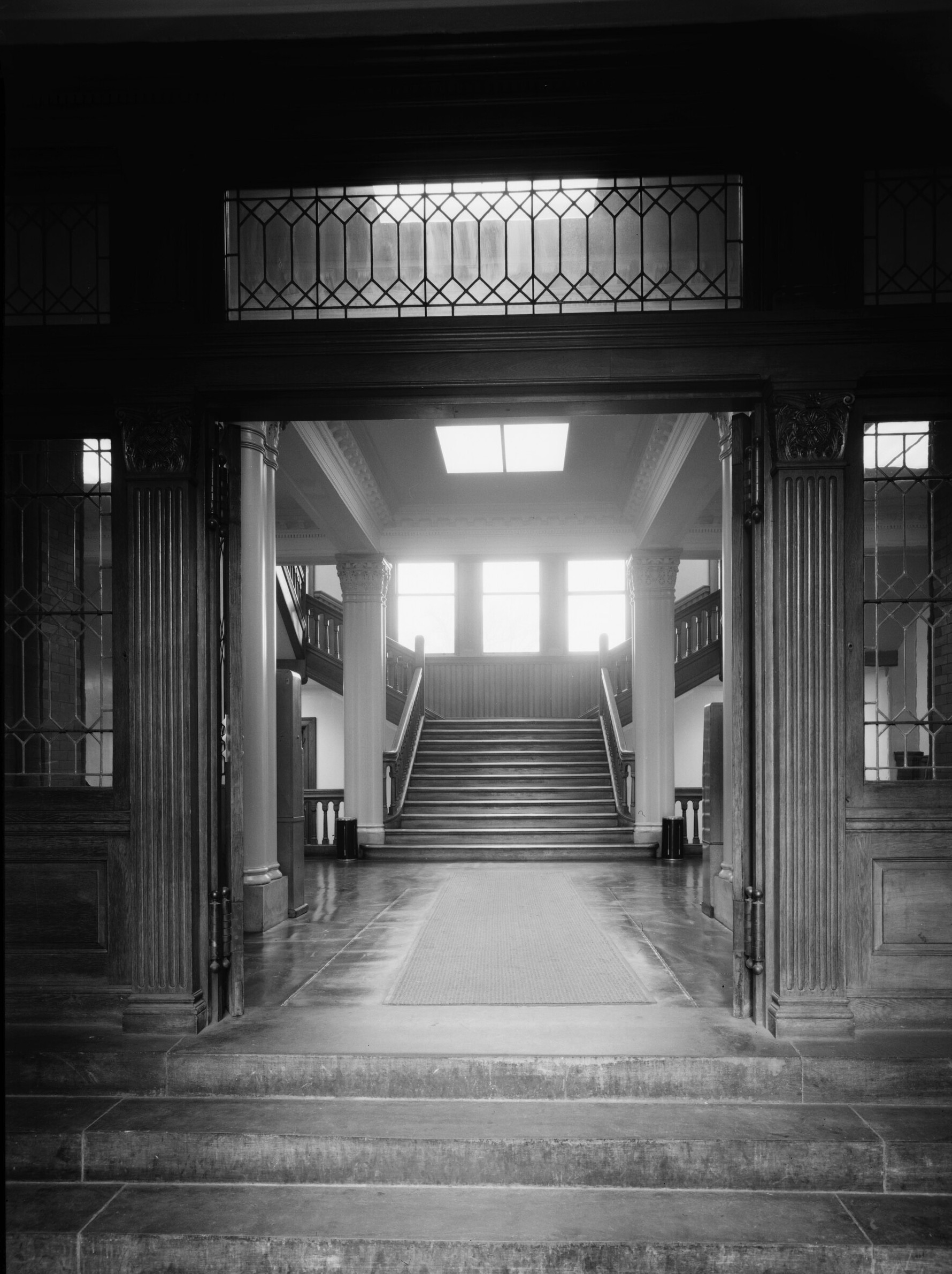The entrance hall of Cambridge City Hall: through open doors, a grand
 staircase rises toward tall, light-filled windows.